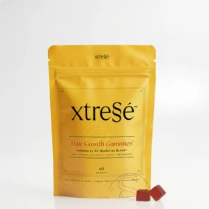 Yellow xtreSé Hair Growth Gummies pouch on a white background with two red gummies beside it
